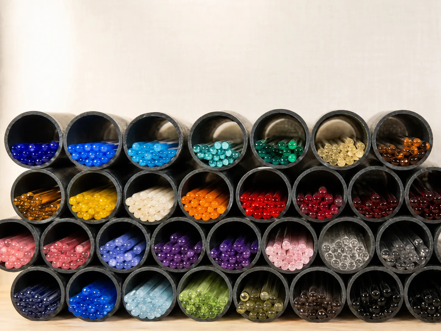 Des tubes empilés en nid d'abeille, remplis de baguettes de verre classées par couleur.