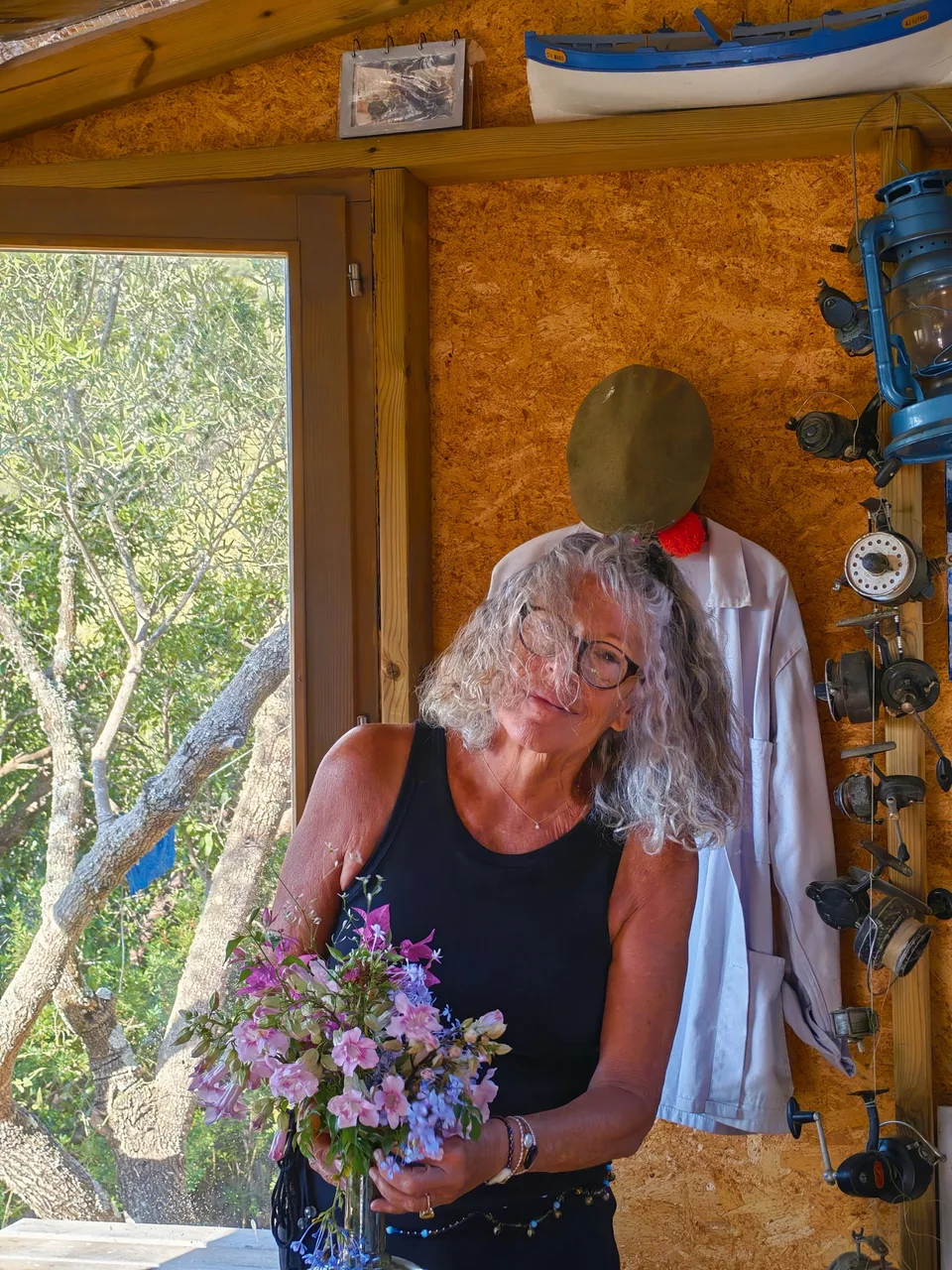 Hélène dans l'atelier, un bouquet de fleurs des champs dans les bras.