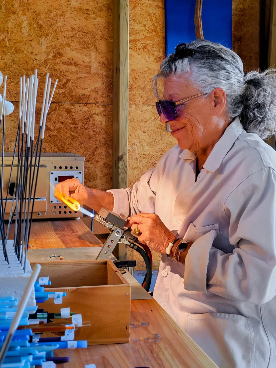 Hélène sourit derrière ses lunettes violettes, une perle dans la flamme du chalumeau.